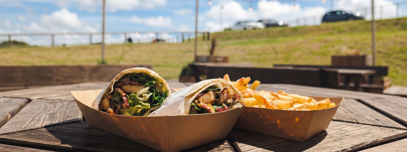 Wrap and chips on an outdoor table at Feed Cafe with blue sky and sunshine